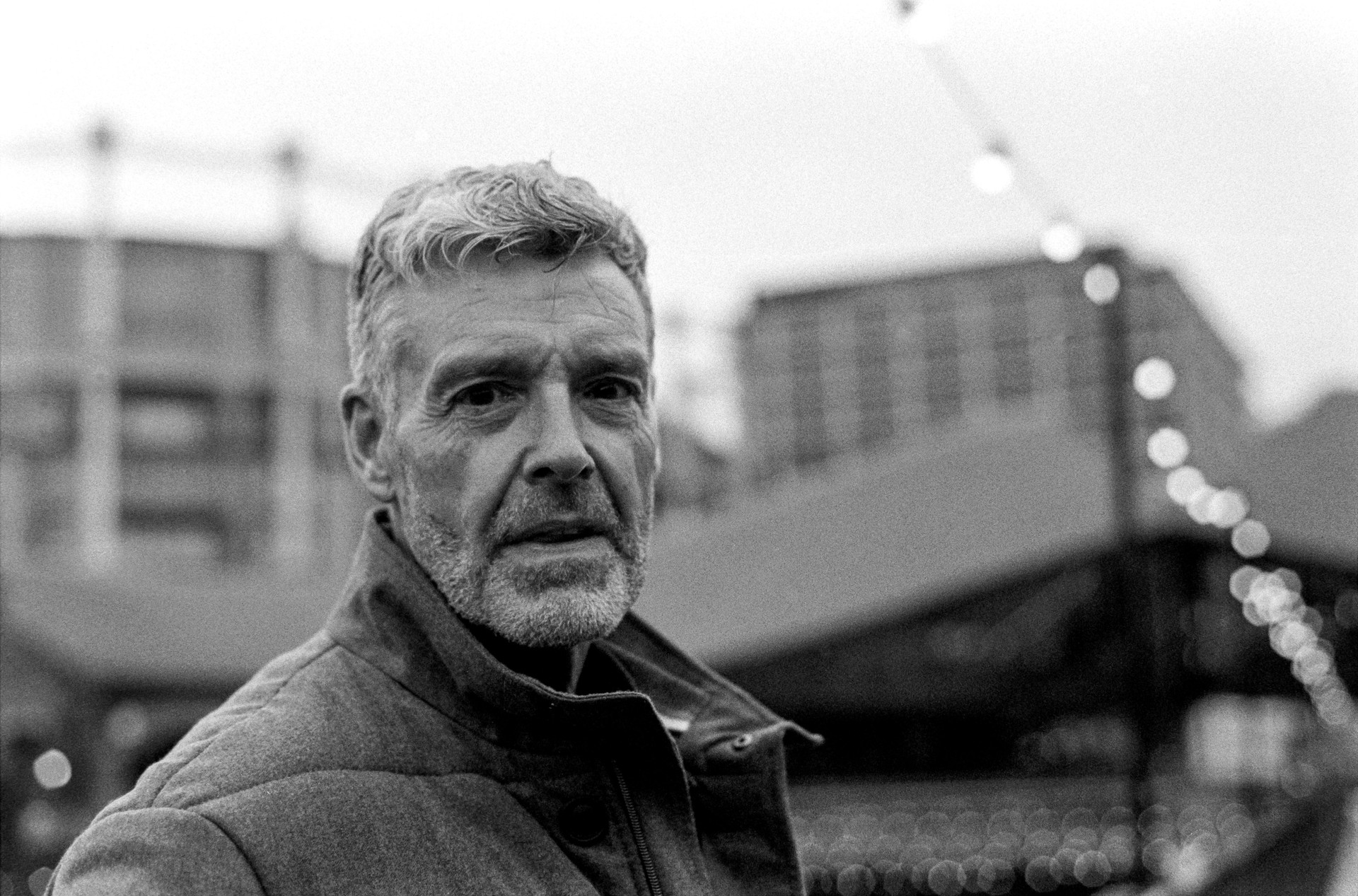 Portrait of a middle-aged man with grey hair and beard in urban setting, grainy black and white analog photography